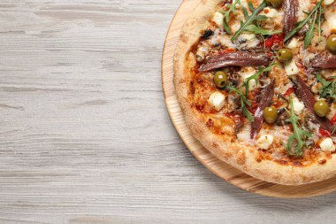 Ançüezli lezzetli pizza, roka ve gri ahşap masadaki zeytinler, üst manzara. Metin için boşluk