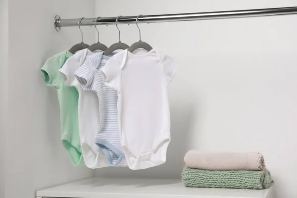 白色墙壁附近挂着婴儿用品和成堆的衣服的吊床 案文的篇幅 — 图库照片