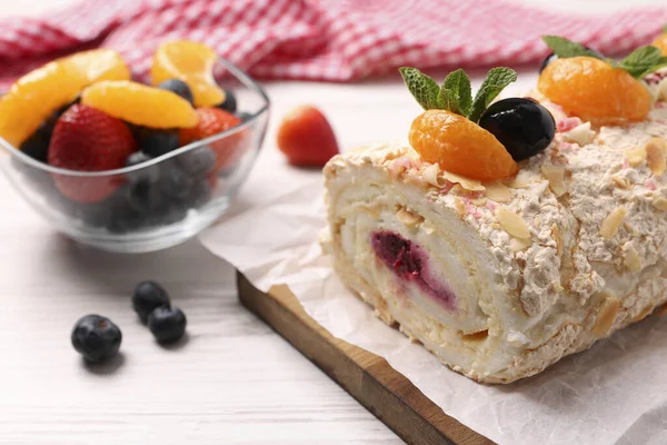 stock image Tasty meringue roll with jam, tangerine slices and mint leaves on white wooden table, closeup