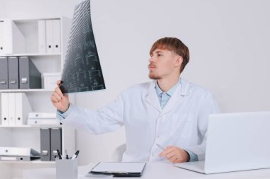 Doktor klinikte boyun MRI görüntüsünü inceliyor.