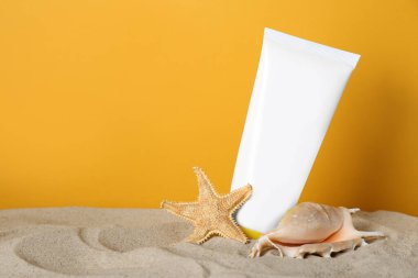 Güneş yanığı ürünü, deniz kabuğu ve deniz yıldızı sarı arka planda. Metin için boşluk