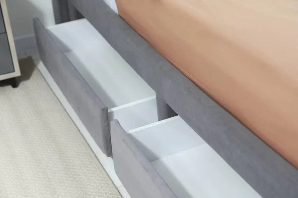 Storage drawers for bedding under modern bed in room, closeup