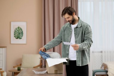 Evinin yakınında tebrik kartı olan mutlu bir adam. İnternet alışverişi