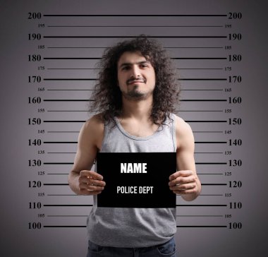 Suçlu sabıkalı fotoğrafı. Yükseklik çizelgesine karşı boş kartı olan tutuklu bir adam