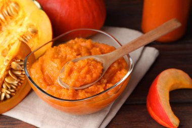 Bir kase balkabağı reçeli ve ahşap masada taze balkabağı.