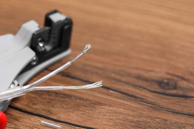 Cutters and stripped wire on wooden table, closeup. Space for text