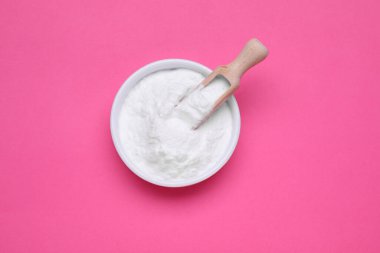 Pembe arka planda bir kase tatlı toz früktoz, üst manzara.