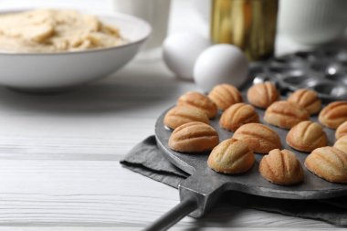 Lezzetli ceviz şekilli kurabiyeler ve beyaz ahşap masa üzerindeki malzemeler, yakın plan. Metin için boşluk