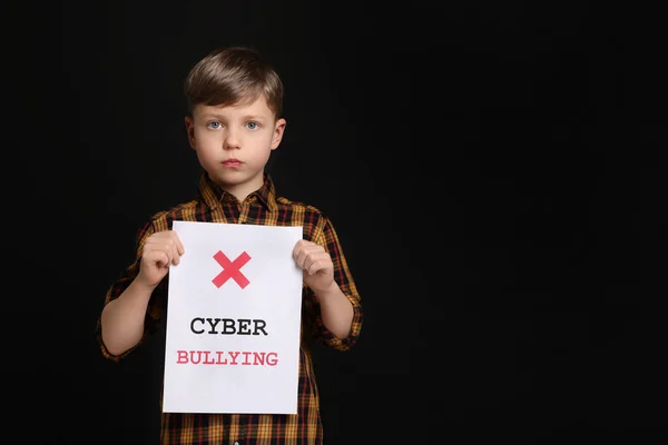 stock image Boy holding sign with phrase Cyber Bullying on black background, space for text