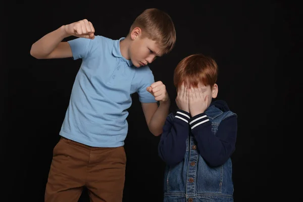 Junge Mit Geballten Fäusten Schikaniert Verängstigtes Kind Auf Schwarzem Hintergrund — Stockfoto