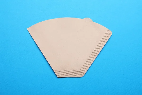 Paper coffee filter on light blue background, top view