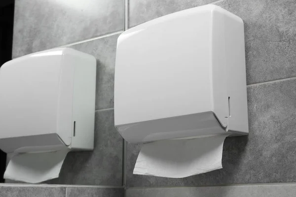New paper towel dispenser hanging on wall near mirror in bathroom