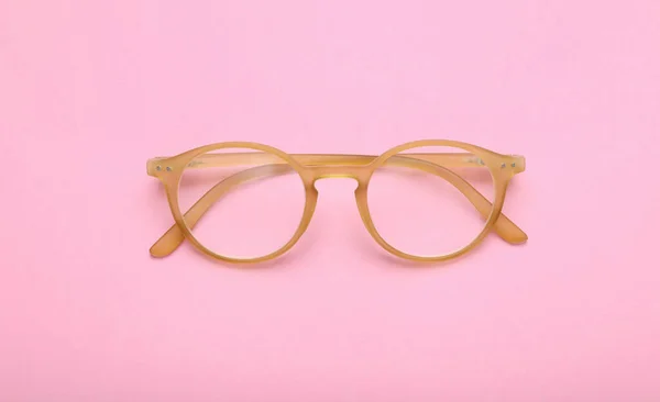 ピンクの背景に補正レンズを持つメガネ トップビュー — ストック写真
