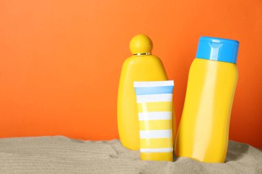 Turuncu arka planda kumdaki farklı güneş ürünleri. Metin için boşluk