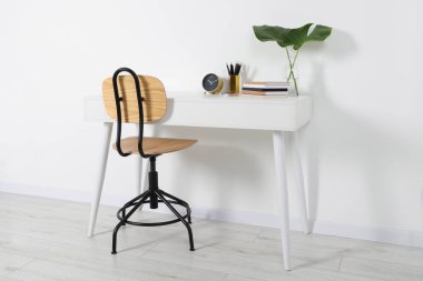 Duvarın yanında beyaz masa olan rahat bir iş yeri.