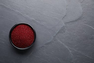 Bir kase koyu kırmızı gıda boyası, gri masa, üst manzara. Metin için boşluk