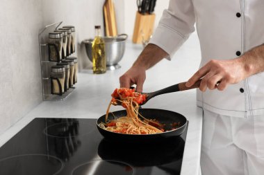 Profesyonel aşçı mutfakta fırında makarna pişiriyor.