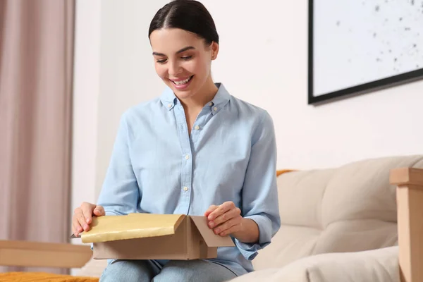 快乐的年轻女人在家里的沙发上打开包裹 网上购物 — 图库照片
