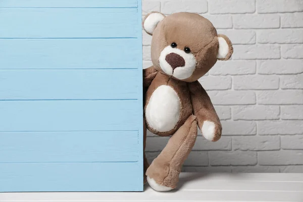 Niedlicher Teddybär Lugt Hinter Hellblauer Holzwand Vor Backsteinhintergrund Hervor Platz — Stockfoto
