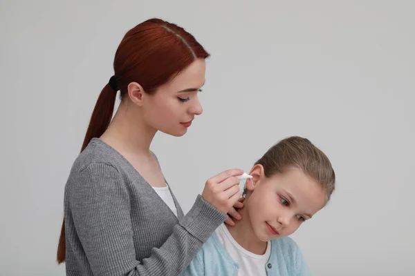Mutter Tropft Ihrer Tochter Auf Hellgrauem Hintergrund Medikamente Ins Ohr — Stockfoto