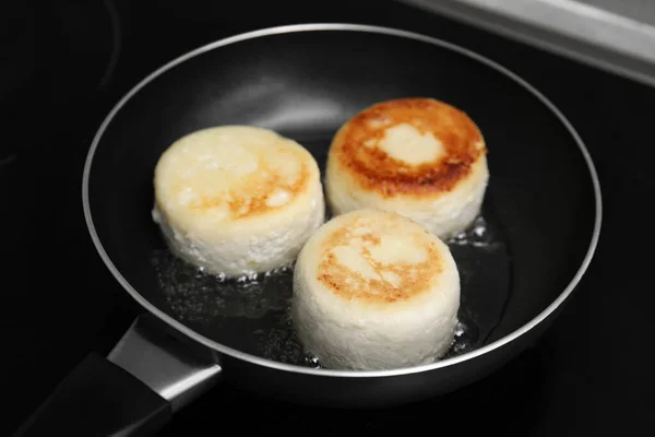 stock image Delicious cottage cheese pancakes in frying pan on cooktop