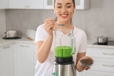 Mutfaktaki lezzetli smoothie 'ye chia tohumu ekleyen güzel genç kadın, blender' a odaklan.
