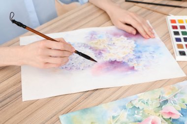 Ahşap masada suluboya çiçeklerle resim yapan kadın, yakın plan. Yaratıcı sanat eserleri