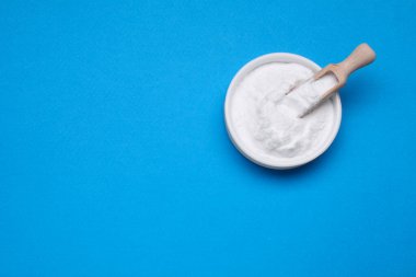 Açık mavi arka planda bir kase tatlı pudra früktoz, üst manzara. Metin için boşluk