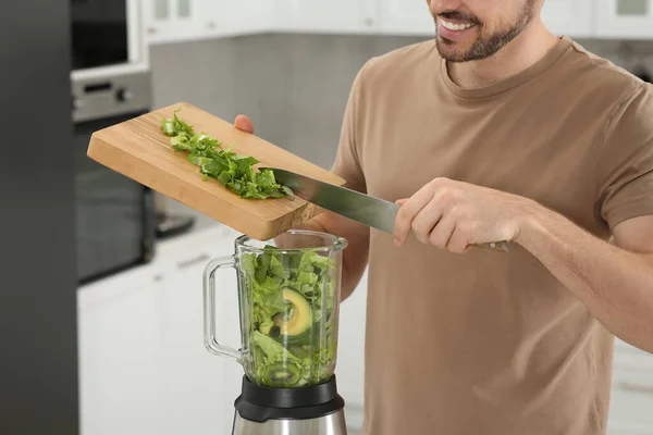 stock image Man adding cut spinach for delicious smoothie in kitchen, closeup