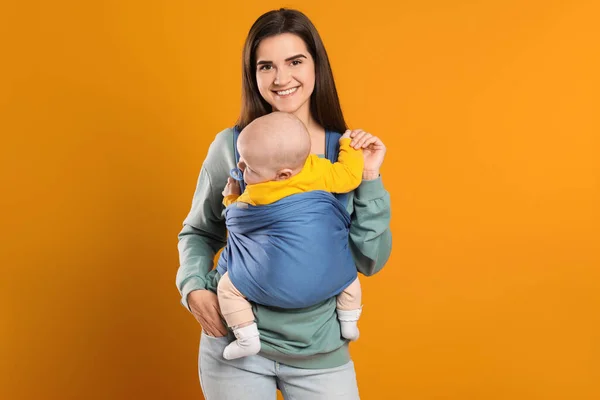 Moeder Houdt Haar Kind Draagdoek Babydrager Oranje Achtergrond — Stockfoto