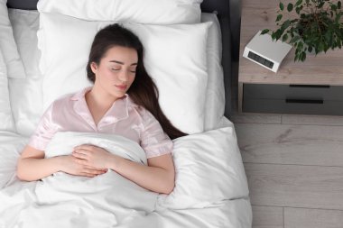 Güzel, genç bir kadın yumuşak bir yatakta uyuyor.