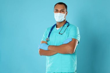 Doctor or medical assistant (male nurse) with protective mask and stethoscope on turquoise background. Space for text