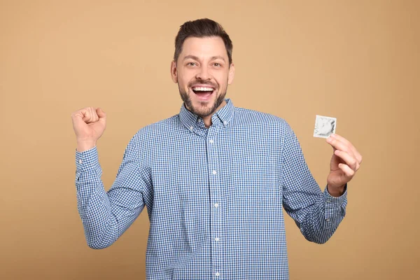 Excited Man Holding Condom Beige Background — Stock Photo, Image