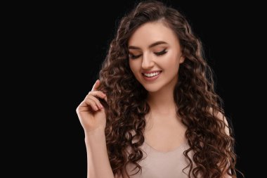 Kahverengi arka planda uzun kıvırcık saçlı güzel bir genç kadın.