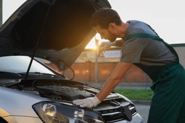 Worker checking motor oil level with dipstick outdoors