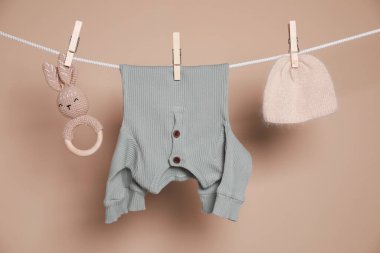 Şirin bebek kıyafetleri ve oyuncak kahverengi arka planda çamaşır ipine asılı.