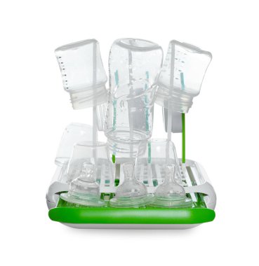 Açık gri masada beyaz arka planda kısırlaştırmadan sonra bebek şişeleri ve meme uçları olan kurutucu.