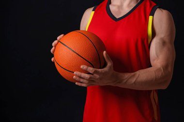 Siyah arka planda basketbol topu olan atletik adam, yakın plan.