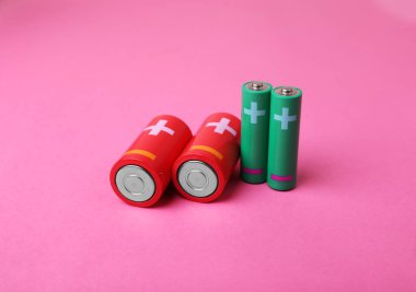 Yeni AA ve C, pembe arkaplandaki pilleri ölçer