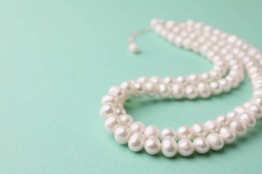 Turkuaz arka planda zarif inci kolye, yakın plan. Metin için boşluk