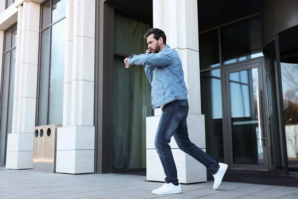 Homem Emocional Falando Smartphone Olhando Para Assistir Enquanto Corre Prédio — Fotografia de Stock
