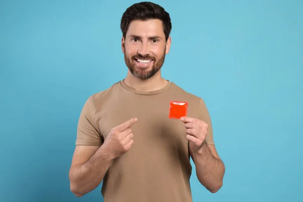 Homem Feliz Segurando Preservativo Fundo Azul Claro Sexo Seguro — Fotografia de Stock