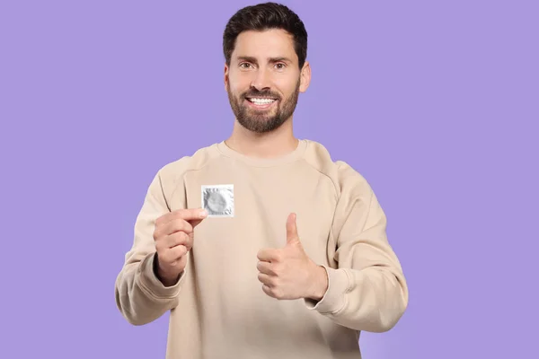 Щасливий Чоловік Презервативом Показує Великий Палець Фіолетовому Тлі Безпечний Секс — стокове фото