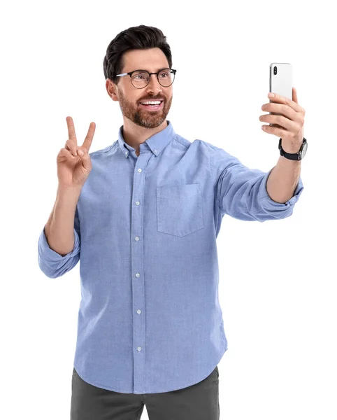 微笑的男人拿着智能手机自私自利 在白色背景上展示和平的标志 — 图库照片