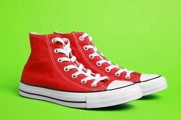 Ζεύγος Νέων Stylish Κόκκινων Sneakers Ανοιχτό Πράσινο Φόντο — Φωτογραφία Αρχείου