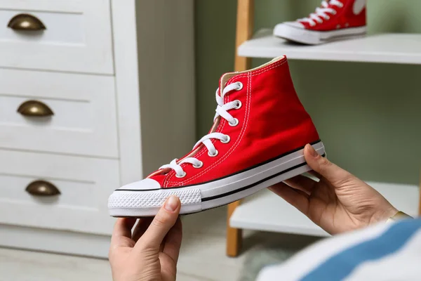 stock image Woman holding new stylish red sneaker indoors, closeup