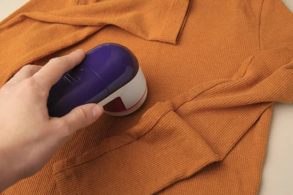 베이지 배경에 주황색 스웨터를 조각을 사용하는 클로즈업 — 스톡 사진