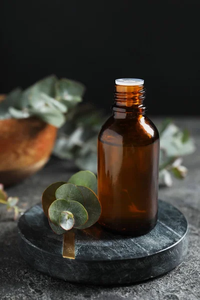 Eine Flasche Ätherisches Eukalyptusöl Und Pflanzenzweige Auf Grauem Tisch — Stockfoto