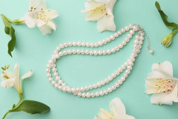 エレガントな真珠のネックレスとターコイズの背景に美しい花とフラットレイ組成物 — ストック写真
