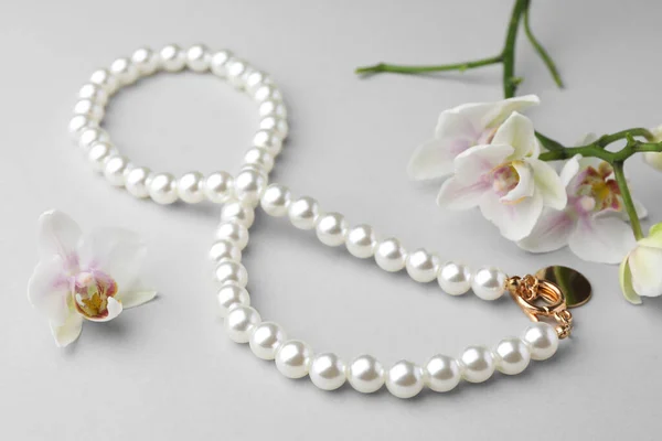 Κομψό Κολιέ Μαργαριτάρι Και Ορχιδέα Λουλούδια Λευκό Φόντο Closeup — Φωτογραφία Αρχείου